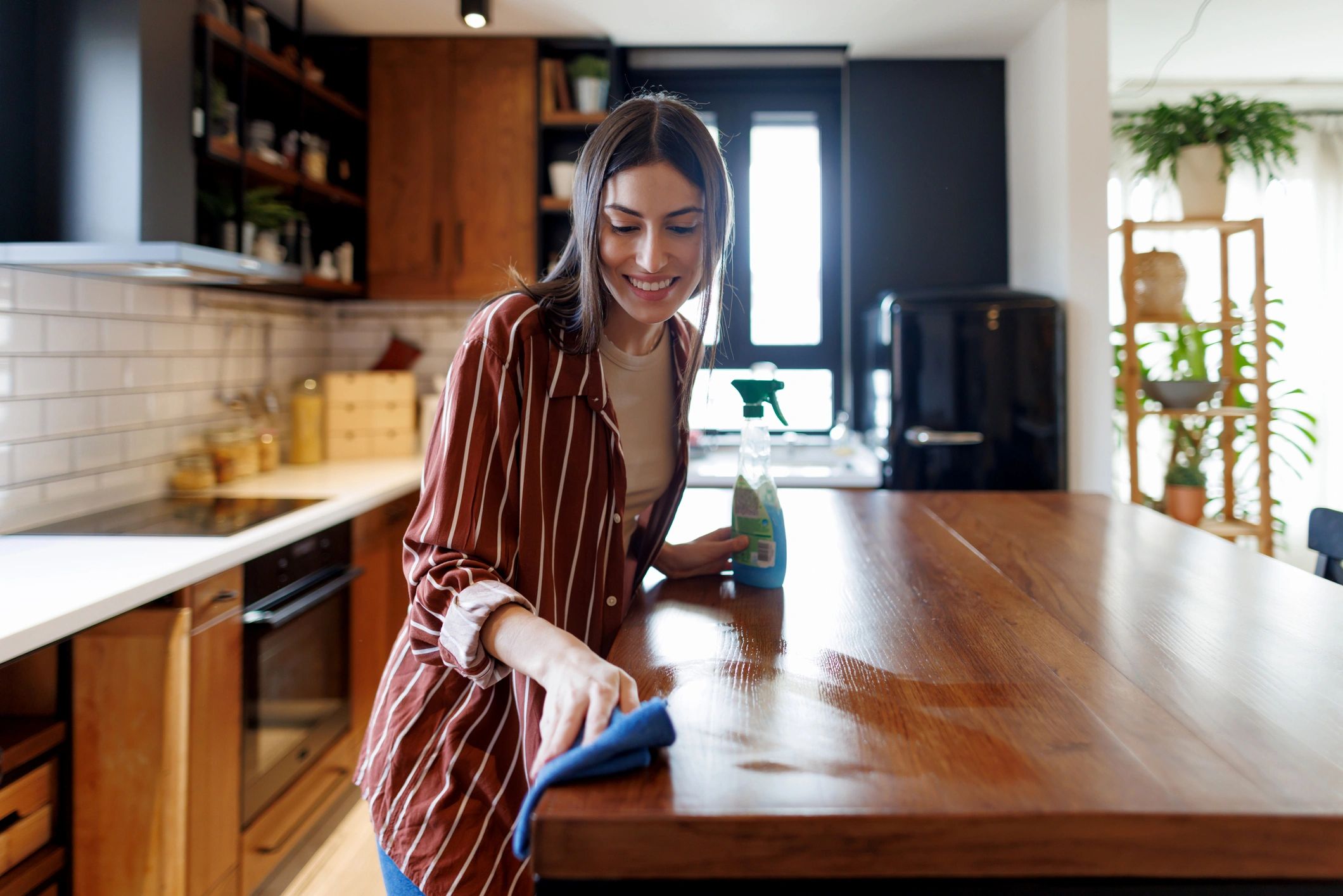 Cleaner wiping a kitchen countertop in a modern home
