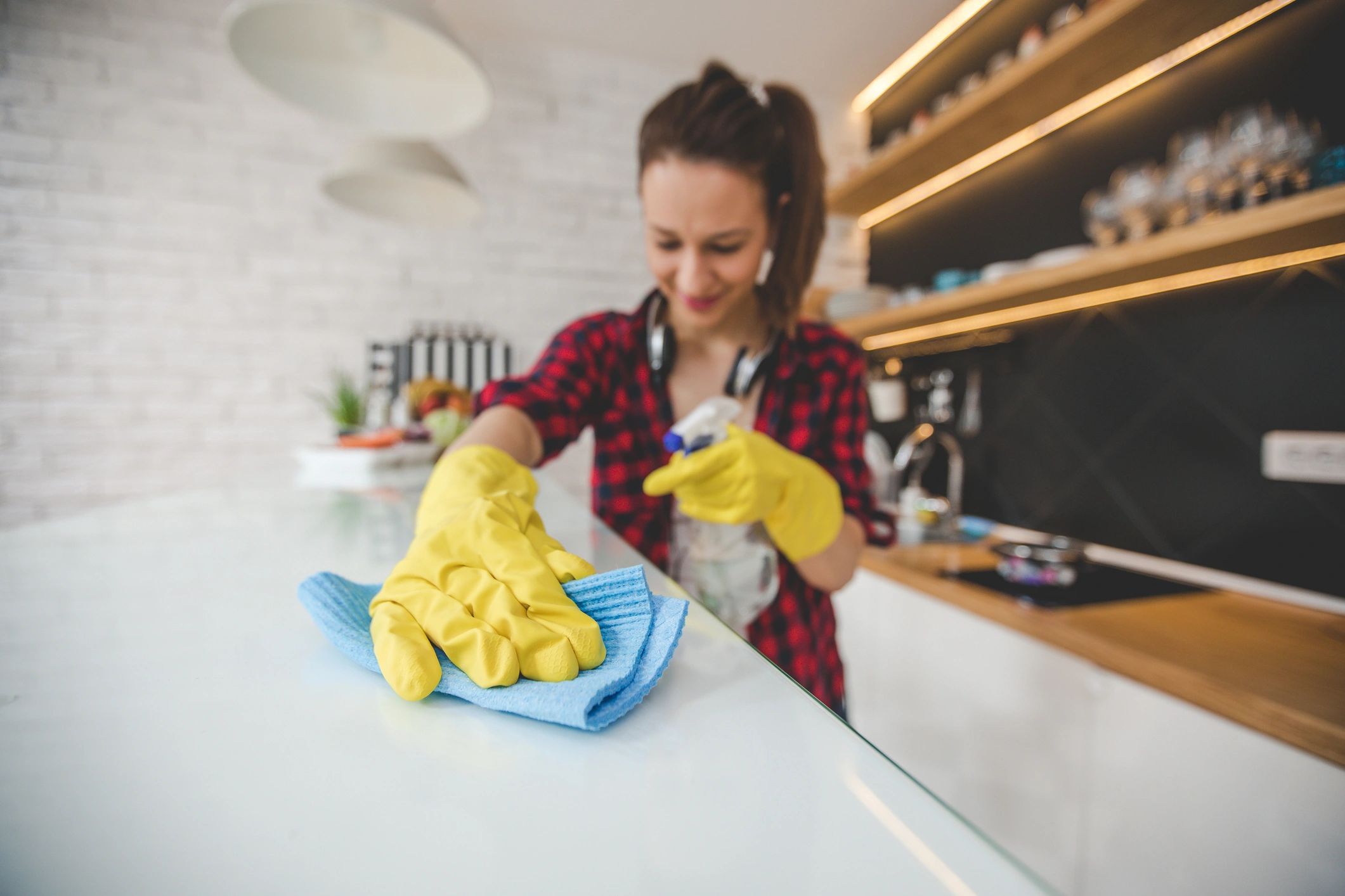 Person cleaning a kitchen surface while wearing headphones